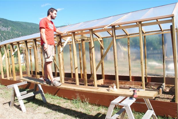 Dan Spark installs plastic sheeting on his greenhouse last summer.  The greenhouse is his new favourite thing.