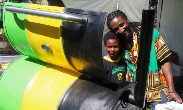 Kamau and his son Khali were keeping the Jamaican food hot before a barbecue painted up in patriotic style at Folkfest.
