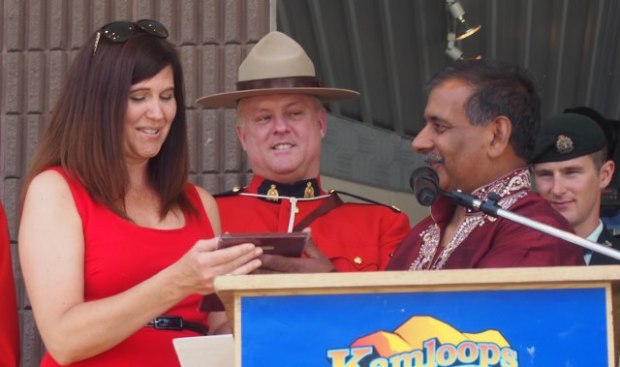 Cheryl Blackwell (left) is presented by Multicultural Society president Ray Dhaliwal with recognition for her many years as emcee at Canada Day, as RCMP Cpl. Bob Jones looks on.