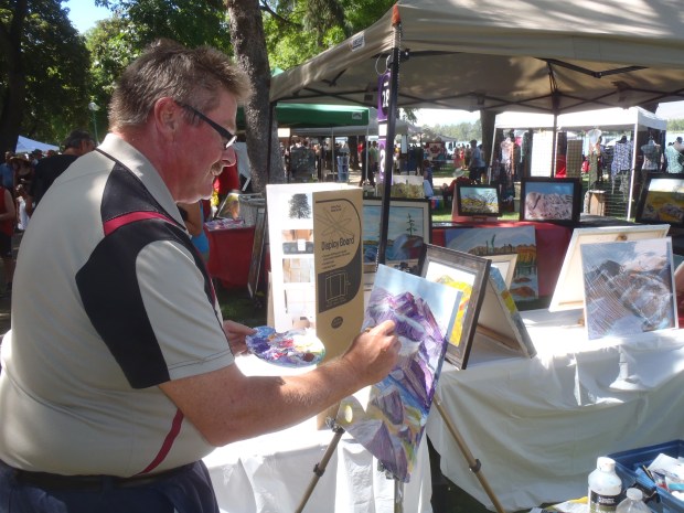 Artist Thor Fredrickson works on an oil painting in Art in the Park.